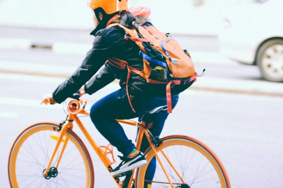 オレンジに統一されたファッションで自転車に乗っている人