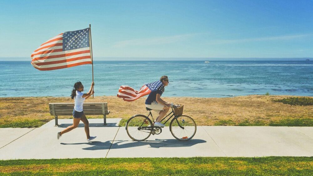 アメリカの国旗をまとって自転車を漕ぐ男性と女性